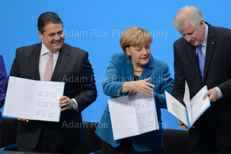 The party heads with their signed copies of the coalition contract. Merekel (CDU) helps Seehofer (CSU) while he struggles a bit and Gabriel (SPD) laughs on