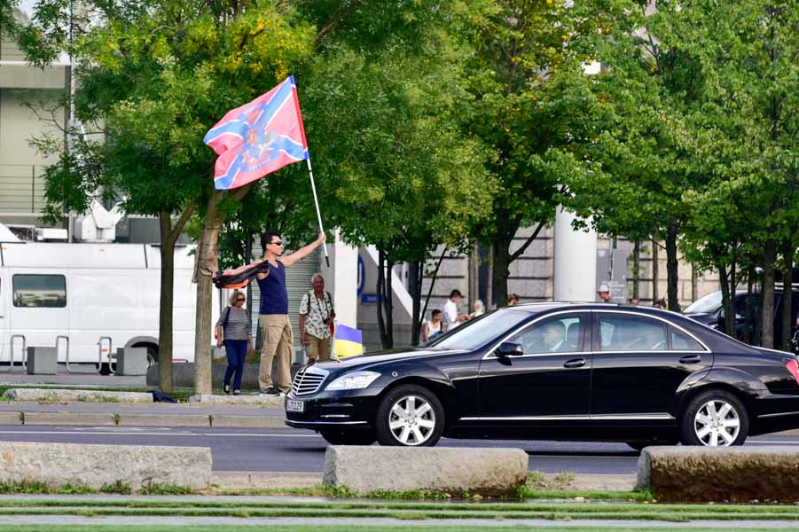 An odd welcome: A man waves the separatist flag of Novorossiya in Berlin as the motorcade carrying Ukrainian President Petro Poroshenko passes by en route to Merkel's offices.