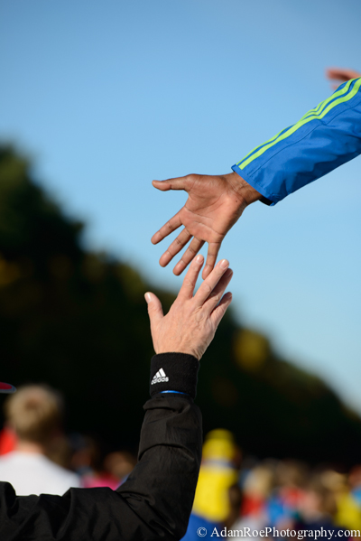 Previous world record holder Patrick Makau reaches down to greet a runner