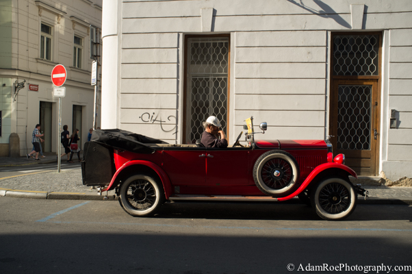 A driver takes a break from ferrying tourists around town in a classic red convertible.